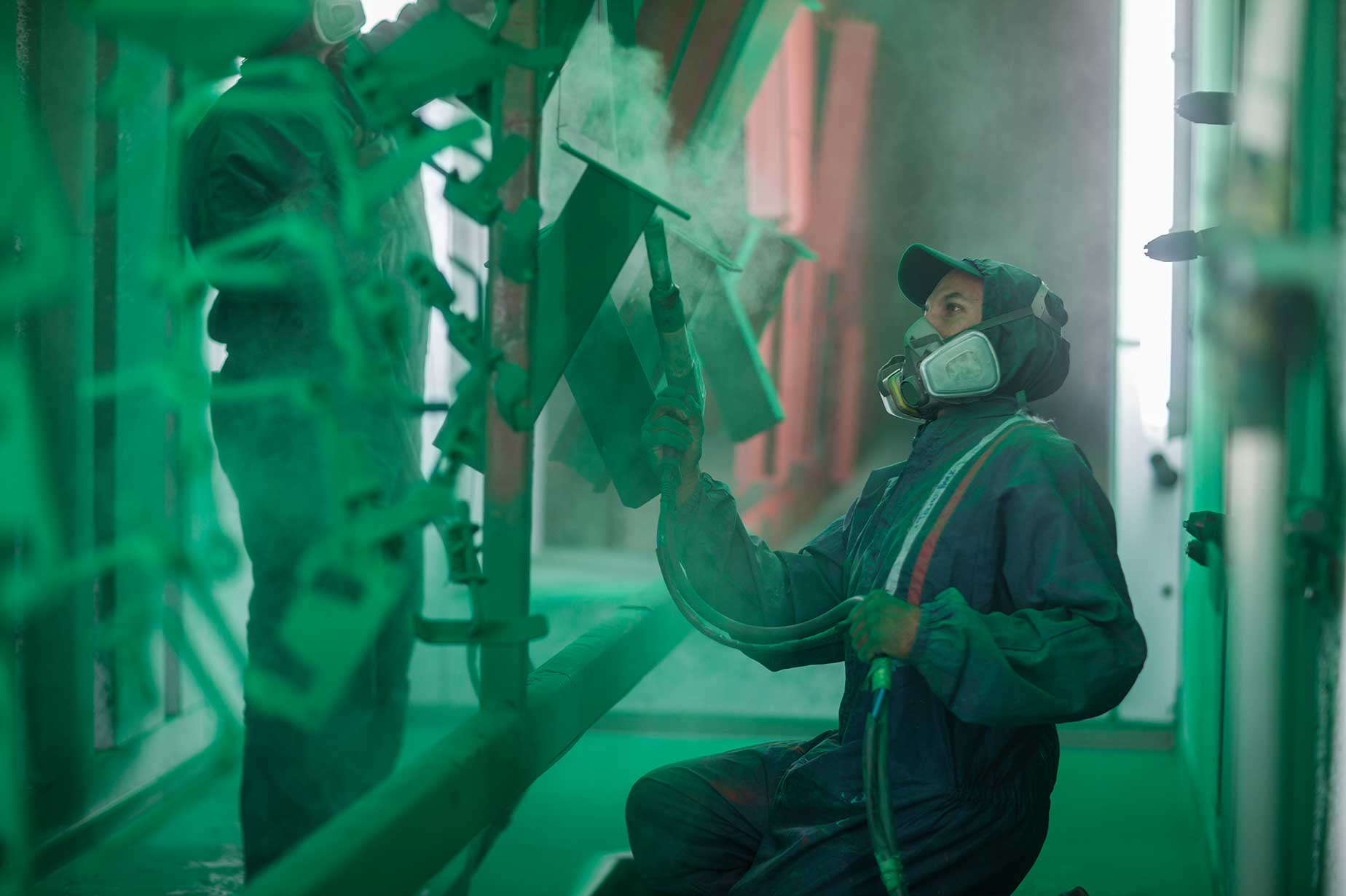 Painters spraying steel components in spray booth of a factory