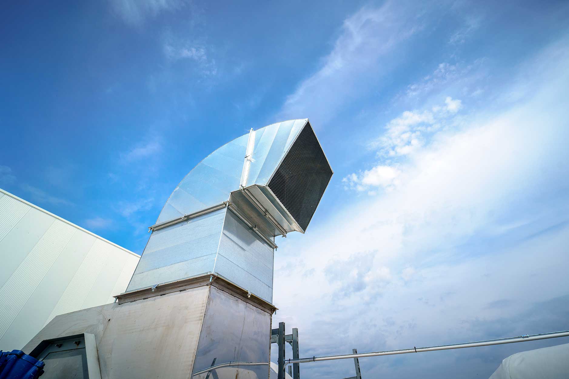 The air conditioning and ventilation system of a large industrial building is located on the roof. Large metal pipes for air duct, air conditioning, smoke removal and ventilation